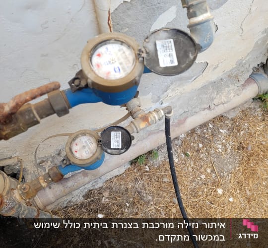 מד מים כחול עם צינורות מחוברים לקיר